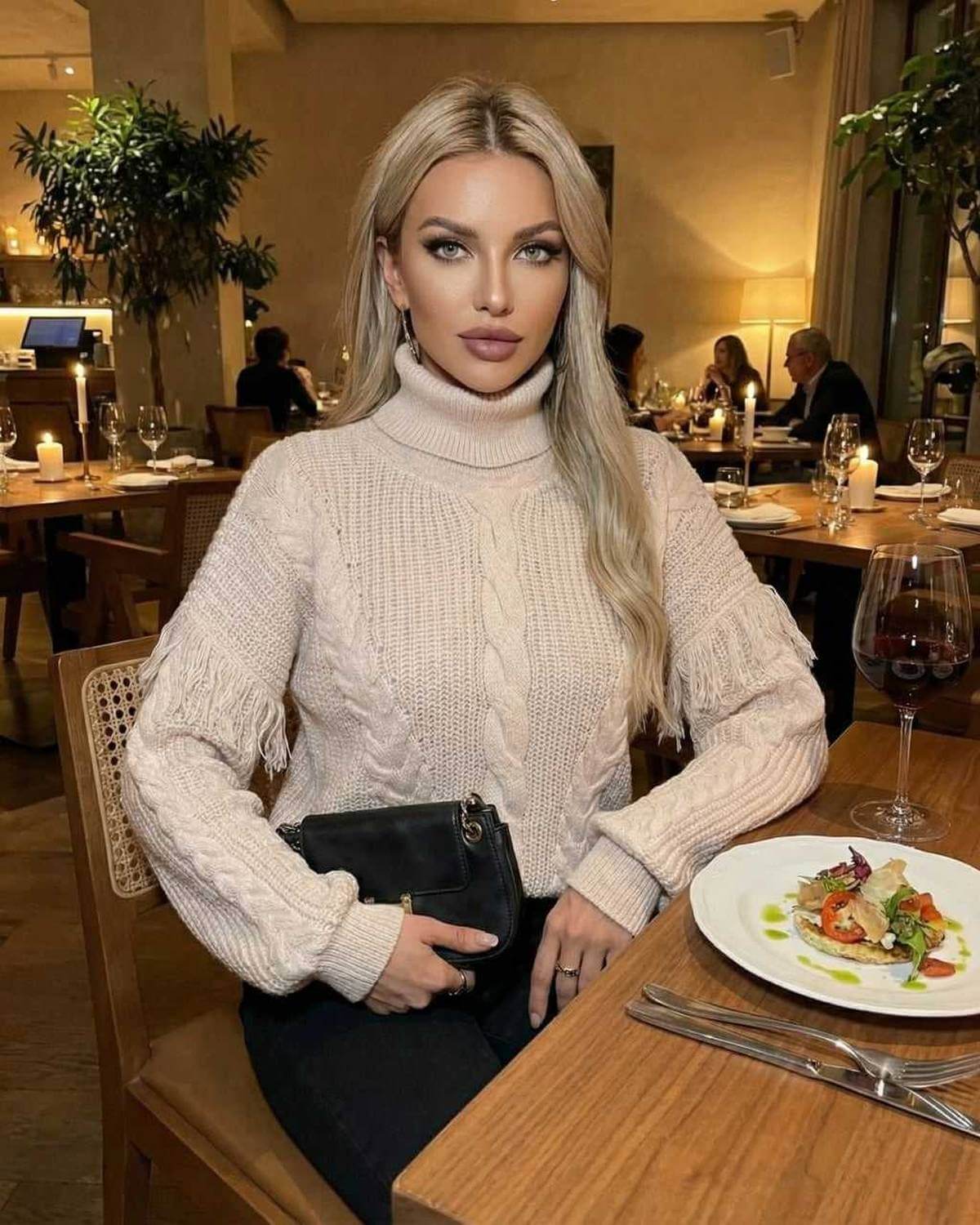 Vienna Sweater by Lauven - Women's beige turtleneck sweater with fringe details, featured in a dining setting.