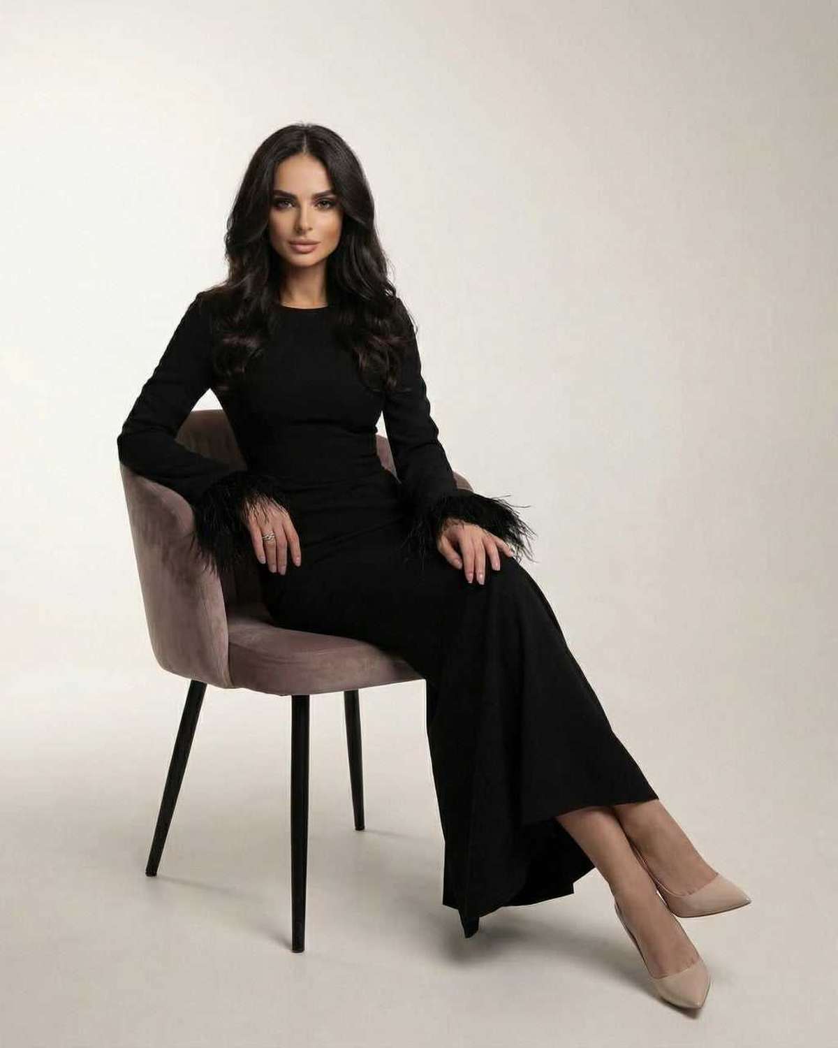 Model wearing Valencia Maxi Dress by Lauven, a black long sleeve mermaid dress with feather cuff sleeves.