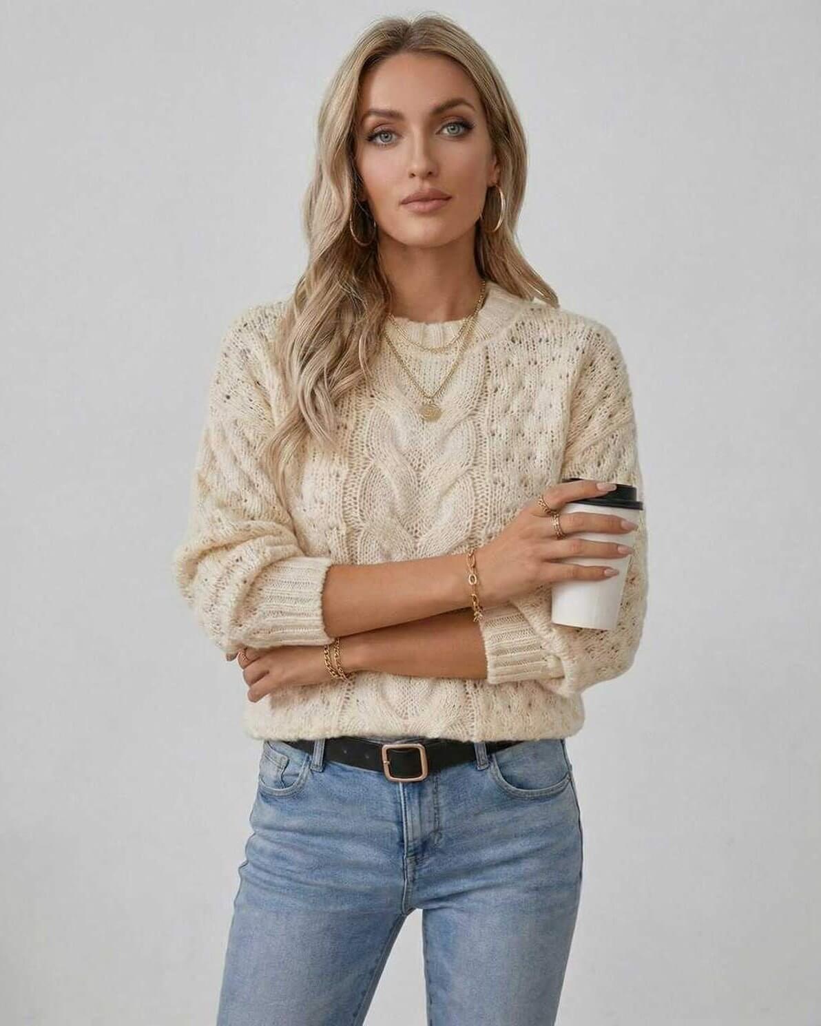 Woman wearing Arden Sweater by Lauven, a cream cable knit pullover with long sleeves and O-neck, holding a coffee cup.