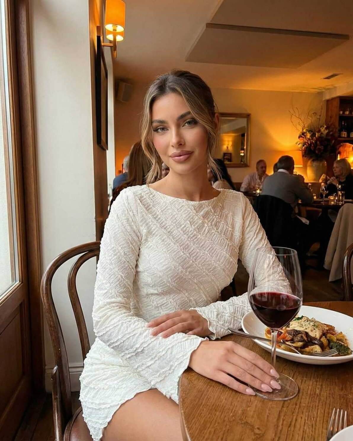 Sienna Mini Dress by Lauven worn by model in a restaurant, showcasing its textured white fabric and A-line silhouette.