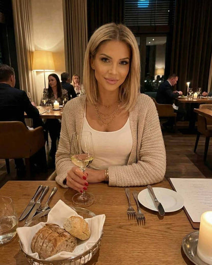 Aspen Cardigan by Lauven: Stylish woman in beige open front cardigan sweater at a cozy dinner setting.