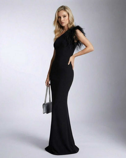 Noirelle Maxi Dress by SLIMONA featuring a one shoulder feather detail and mermaid silhouette.