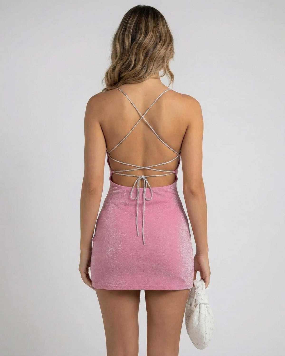 Back view of a model wearing the SLIMONA Rosé Mini Dress with crisscross straps and a soft pink shimmer.