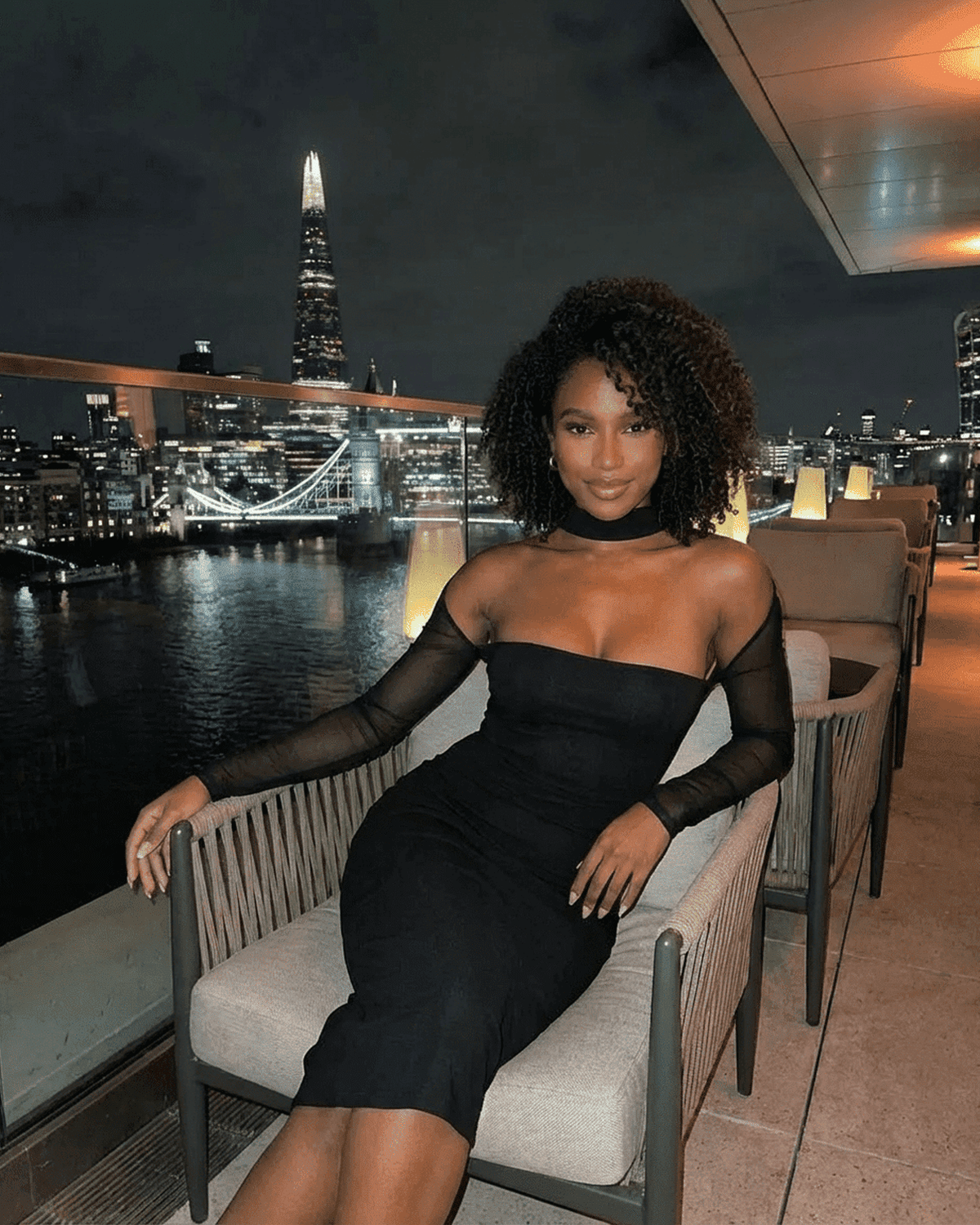 Arden Midi Dress by SLIMONA - Elegant bodycon style with mesh long sleeves and city skyline view.