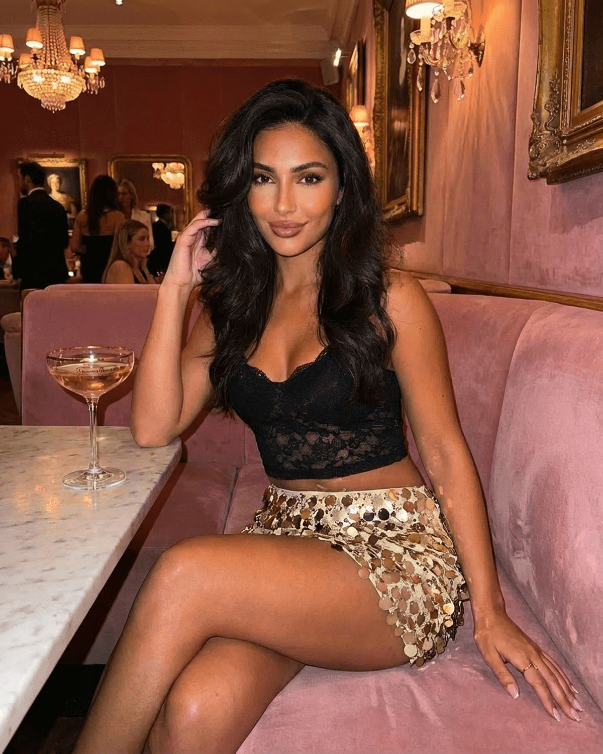 Aurelia Mini Skirt by SLIMONA worn by a woman sitting in a stylish setting, showcasing gold sequin hem and bodycon fit.