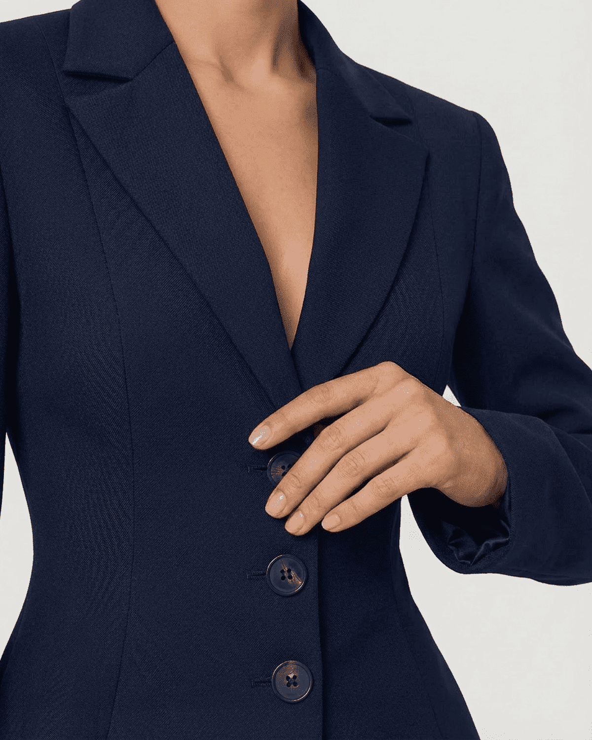 Close-up of a hand fastening buttons on the fitted Aurora Blazer by SLIMONA, showcasing the tailored silhouette.