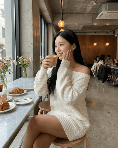 Model wearing the Aurora Mini Dress with off-the-shoulder sleeves, enjoying coffee in a cozy cafe.