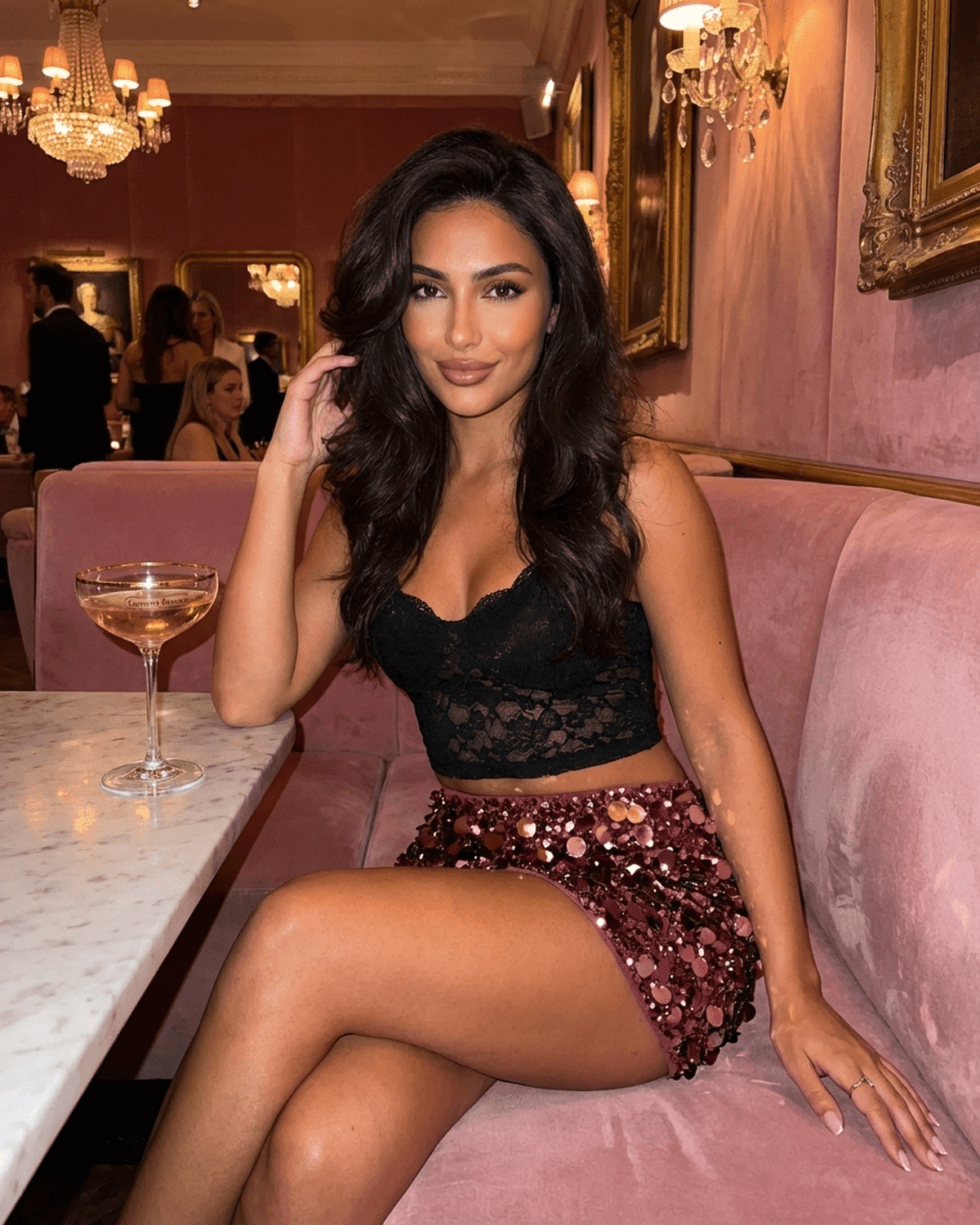 Bordeaux Mini Skirt worn by a woman sitting at a chic venue, showcasing the burgundy sequin hem and bodycon silhouette.