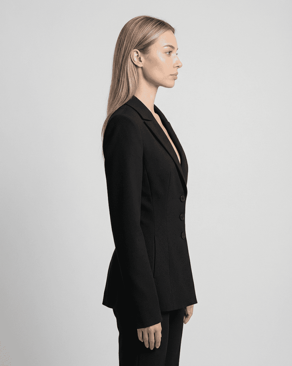 Celeste Blazer by SLIMONA in black, showcasing a fitted waist, V-neck, and tailored silhouette from the side.