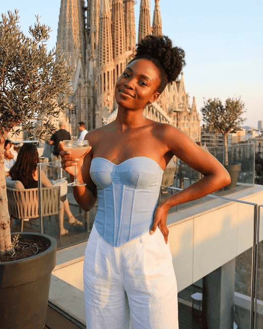 Denali Corset Top by SLIMONA worn by a woman enjoying a drink with a stylish city backdrop.