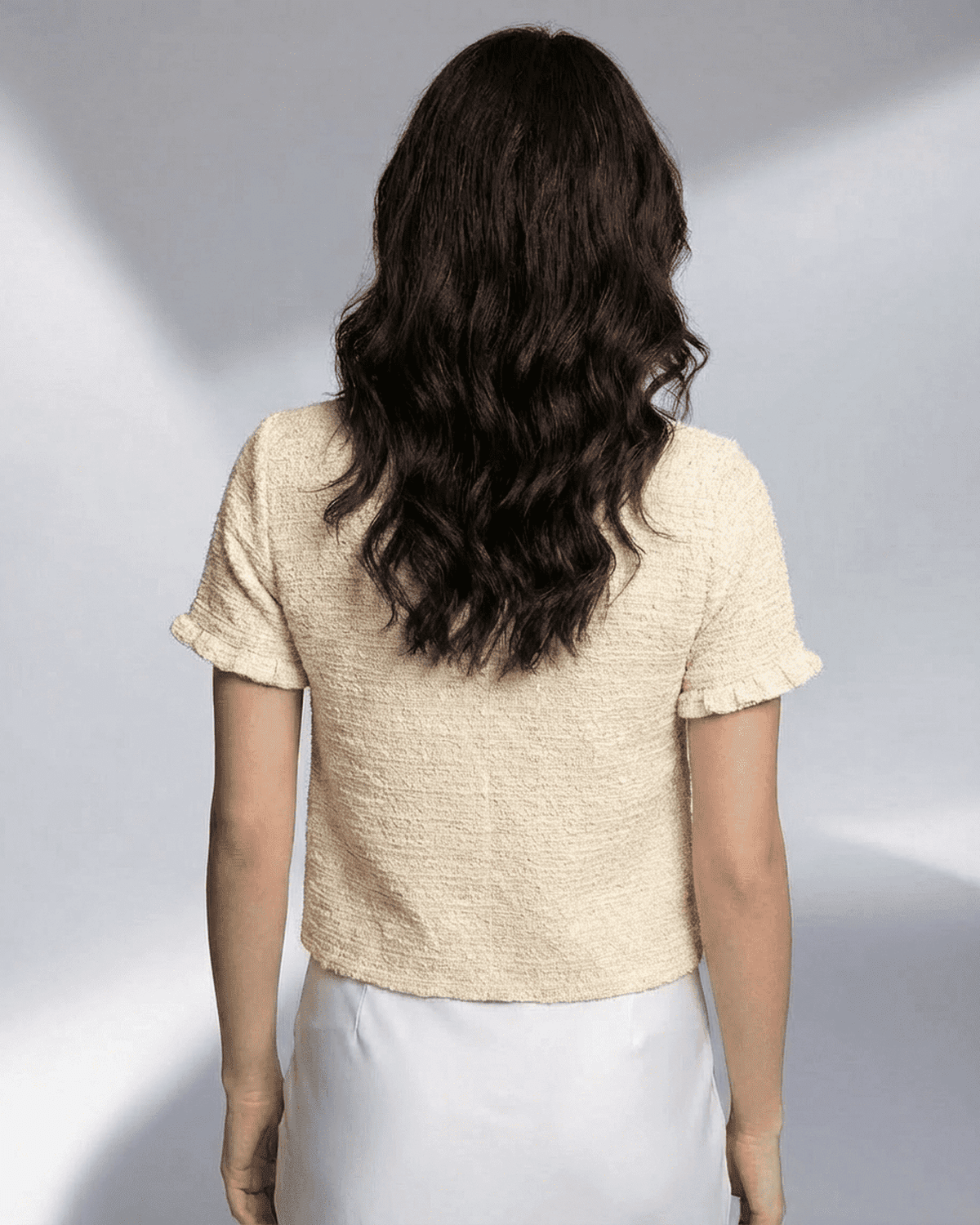 Back view of a woman wearing the SLIMONA Elara Cardigan, showcasing its short sleeve and lightweight knit design.