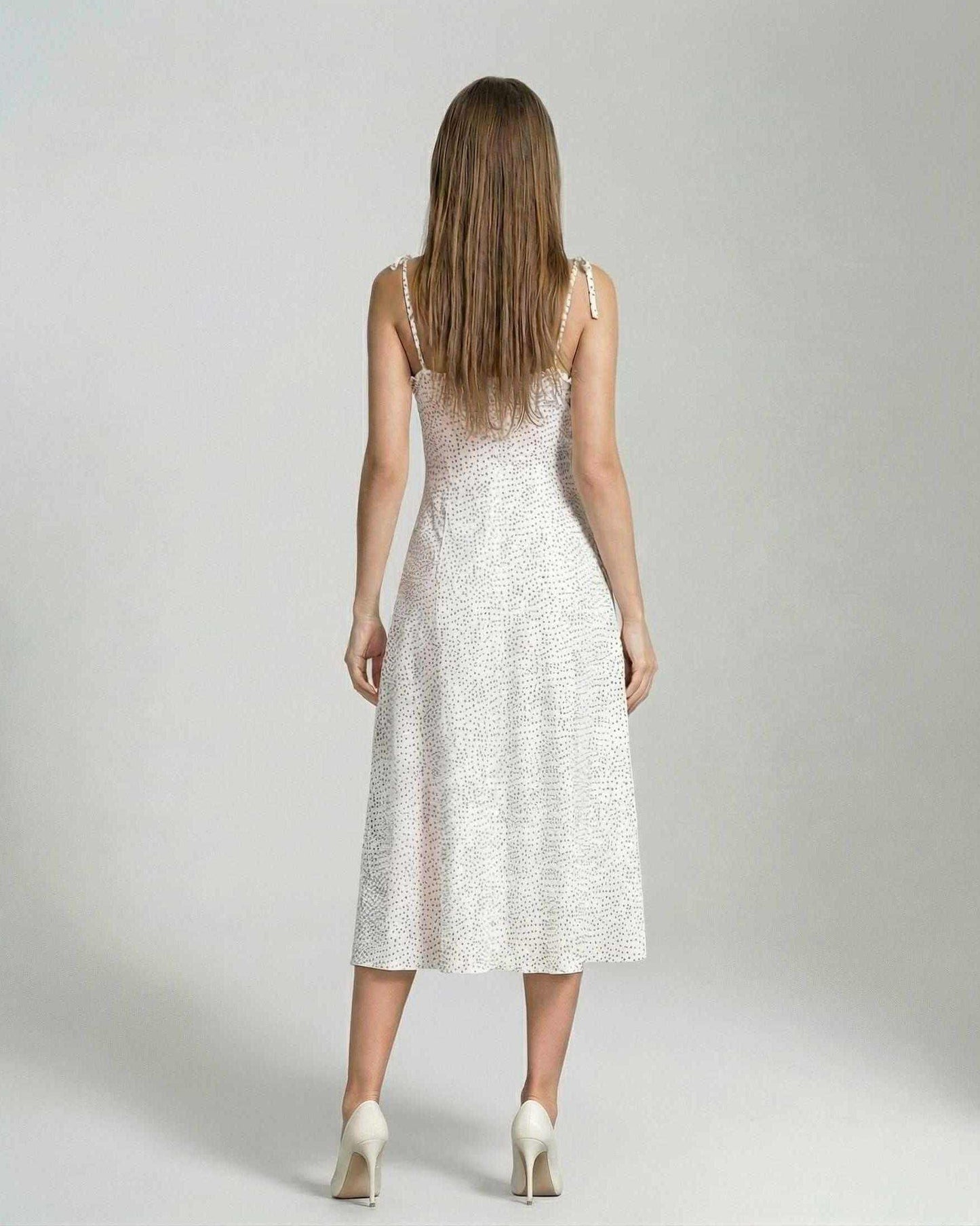 Back view of a woman wearing the Elara Midi Dress by Lauven, showcasing its elegant A-line silhouette with polka dot detail.