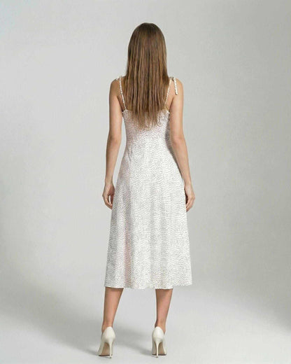 Back view of a woman wearing the Elara Midi Dress by Lauven, showcasing its elegant A-line silhouette with polka dot detail.