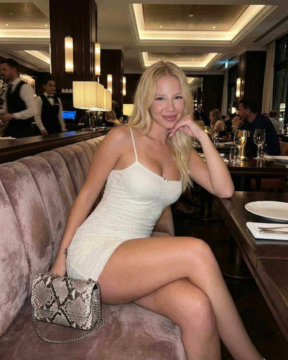 Model wearing Elara Mini Dress by SLIMONA, showcasing elegant lace bodycon design in a modern dining setting.