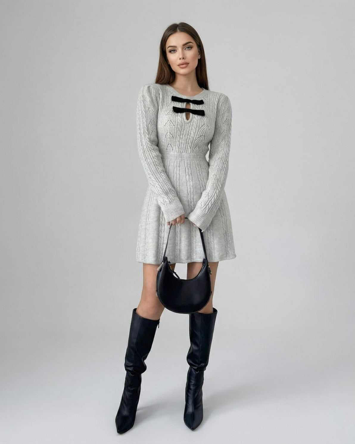 Elara Mini Dress by Lauven featuring a long sleeve knit design with bow detail, styled with a black bag and knee-high boots.