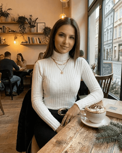 Elara Sweater by SLIMONA - Ribbed turtleneck slim fit knitwear in a cozy café setting.