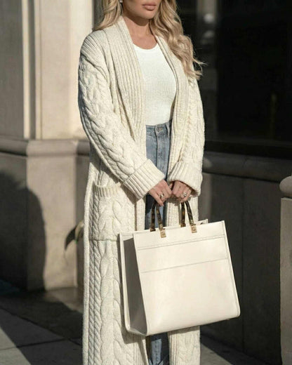 Model wearing the Milano Cardigan by Lauven, a long cable-knit wool blend layer, styled with a white top and chic bag.