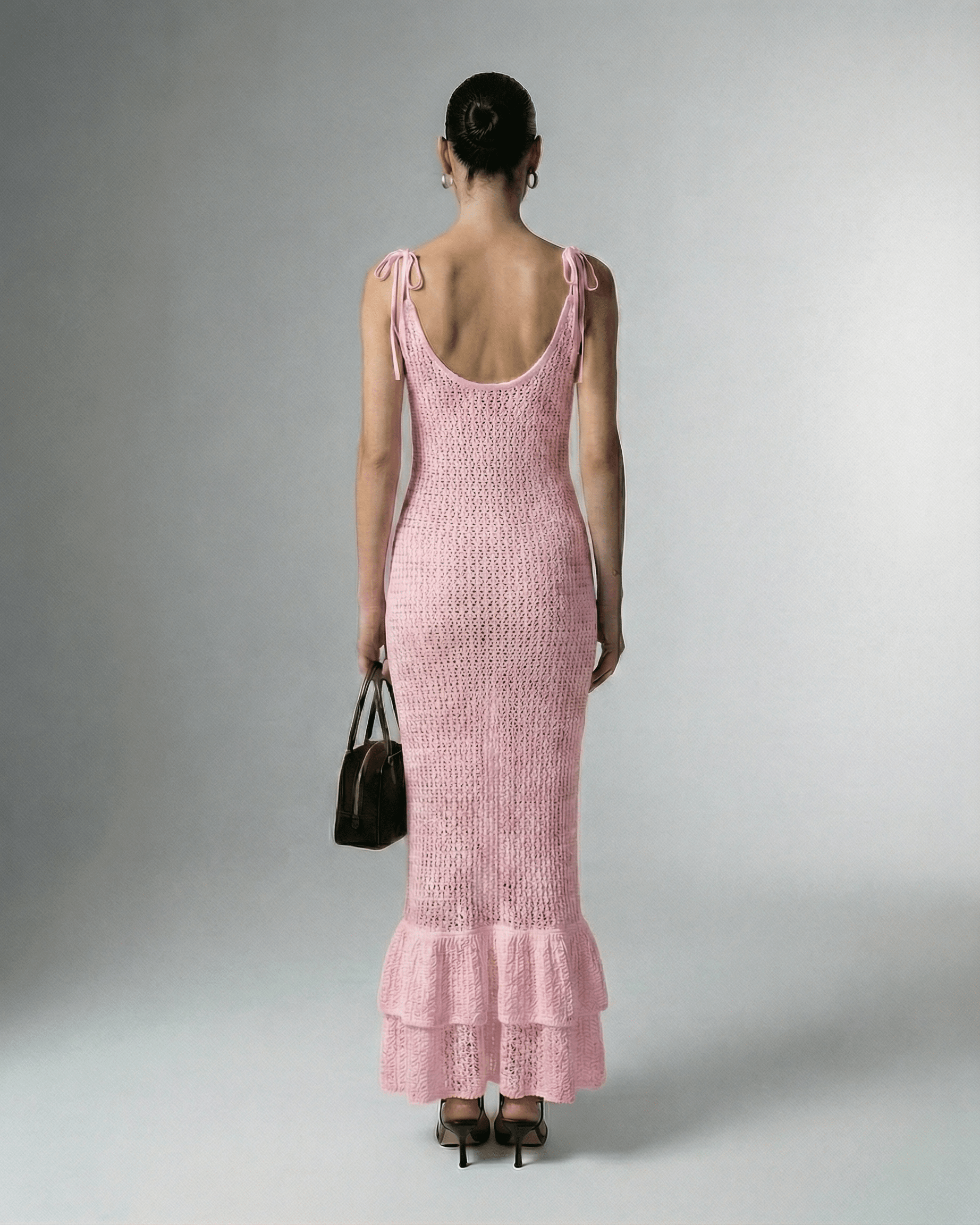 Back view of a model wearing Rosaline Maxi Dress by Lauven, showcasing its stylish pink hollow out knit design.