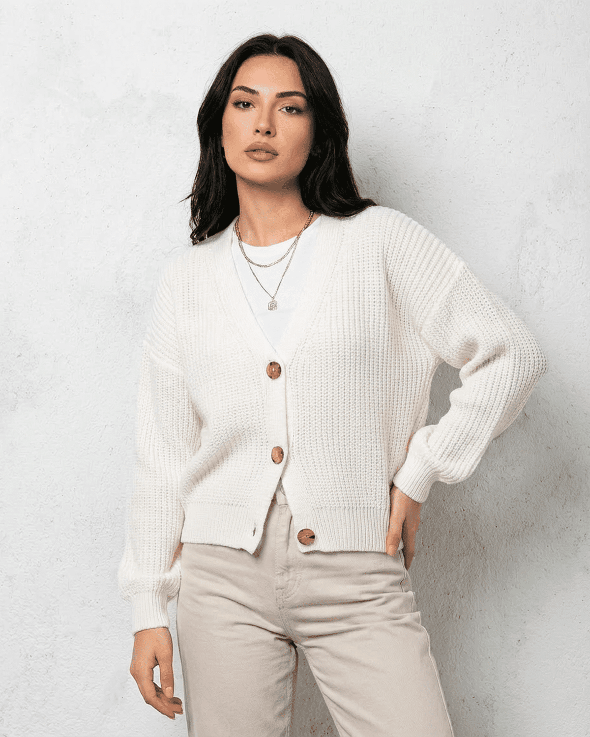 Model wearing the Alba Cardigan by SLIMONA, a classic white knitwear with a soft V-neck design.