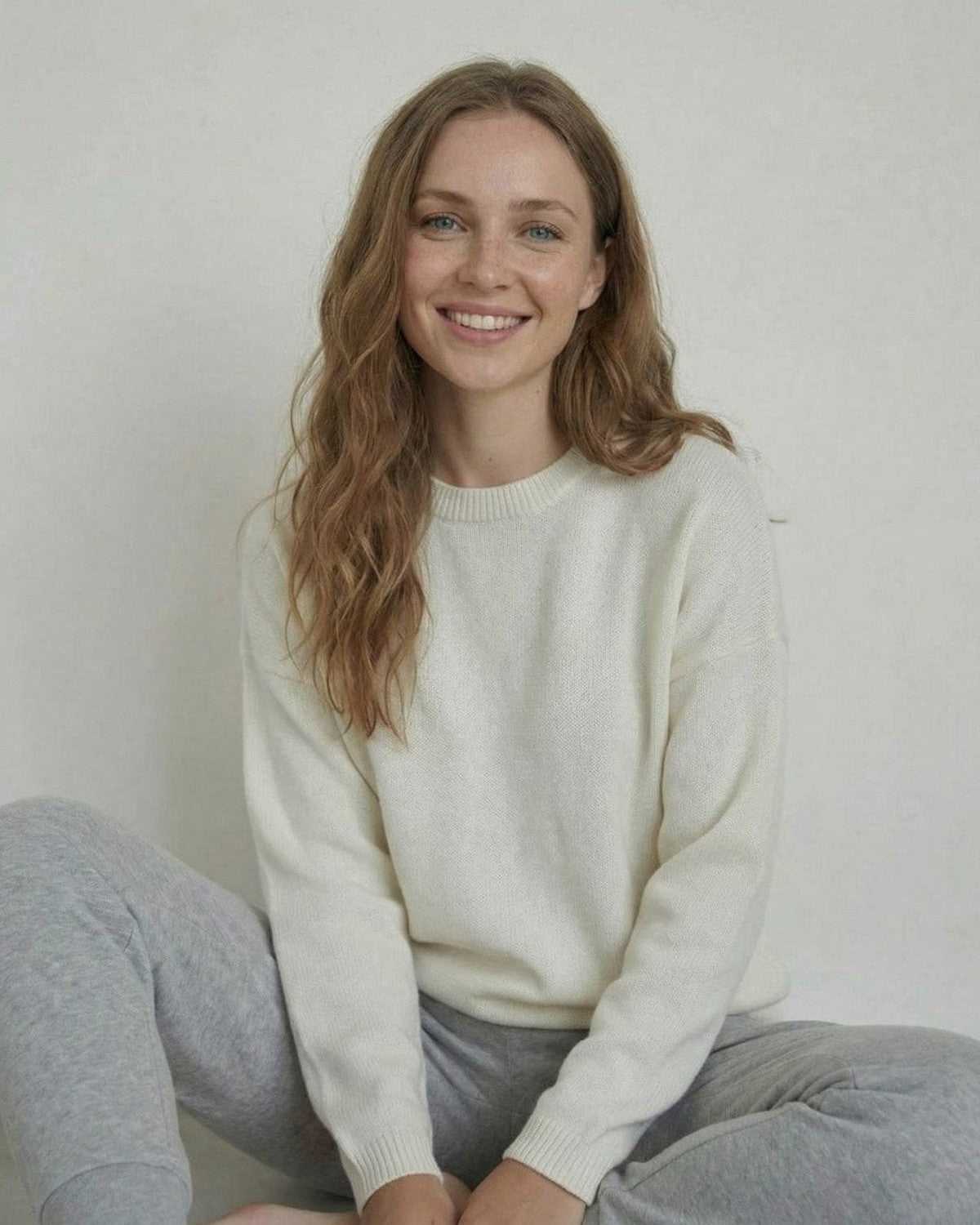 Woman smiling in the Alba Pullover by SLIMONA, a relaxed wool knit sweater for everyday style.