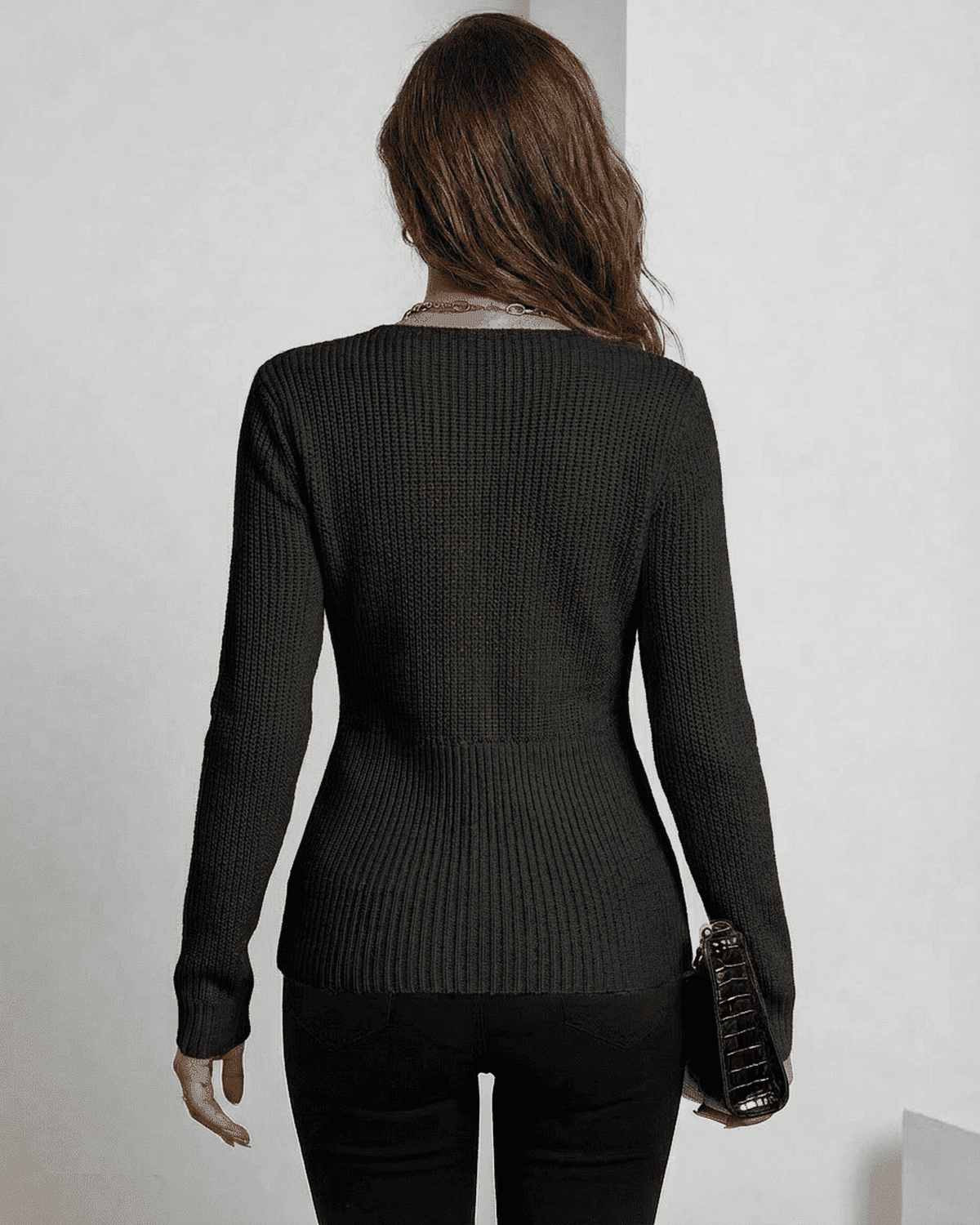 Back view of a woman wearing the Alina Pullover by SLIMONA, showcasing its sleek ribbed design in elegant black.