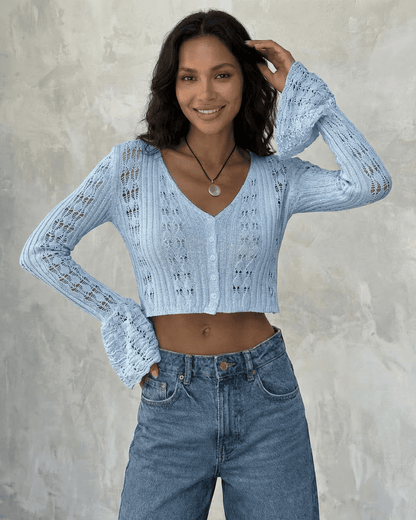 Model wearing Azure Cardigan by SLIMONA, a cropped cotton knit with flare sleeves in light blue.