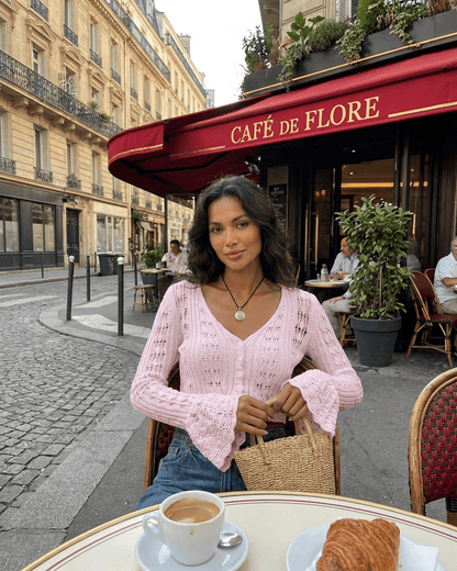 Model wearing a Blossom Cardigan in pink at Café de Flore, showcasing elegant style and relaxed Parisian charm.