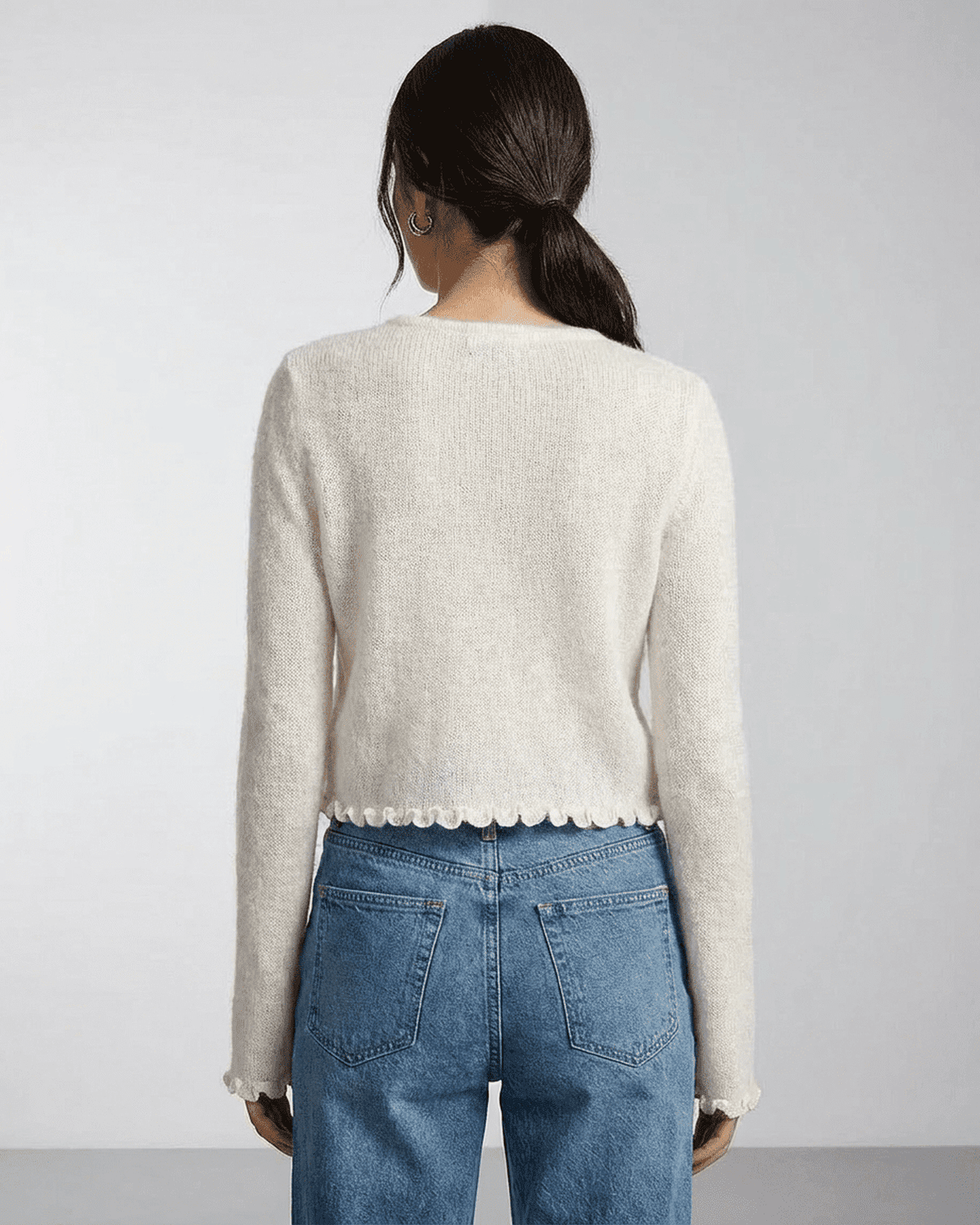 Back view of women wearing the Camellia Cardigan by SLIMONA, showcasing its floral button details and soft knit texture.