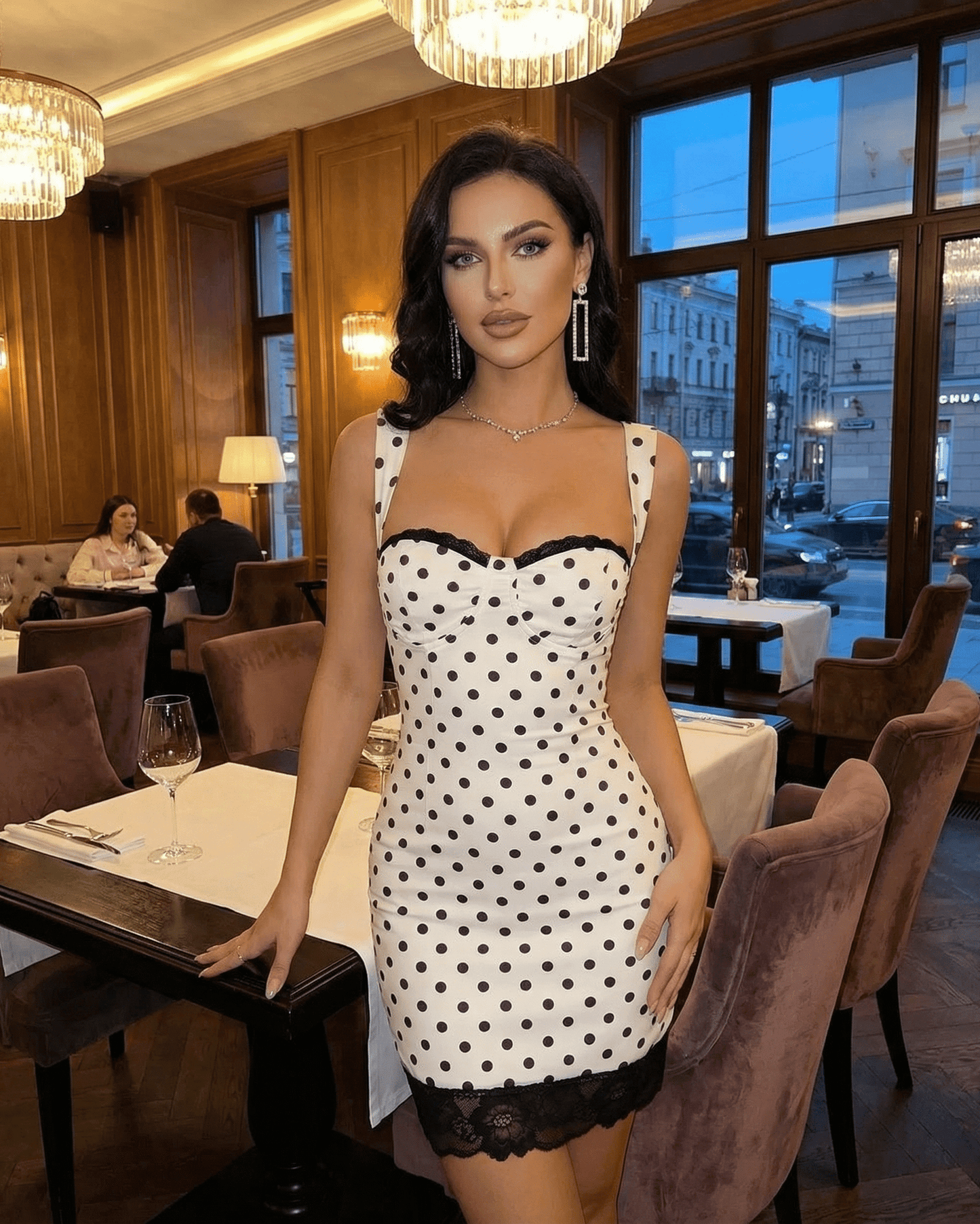 Celeste Mini Dress by SLIMONA, showcasing a polka dot design with lace trim in a stylish restaurant setting.