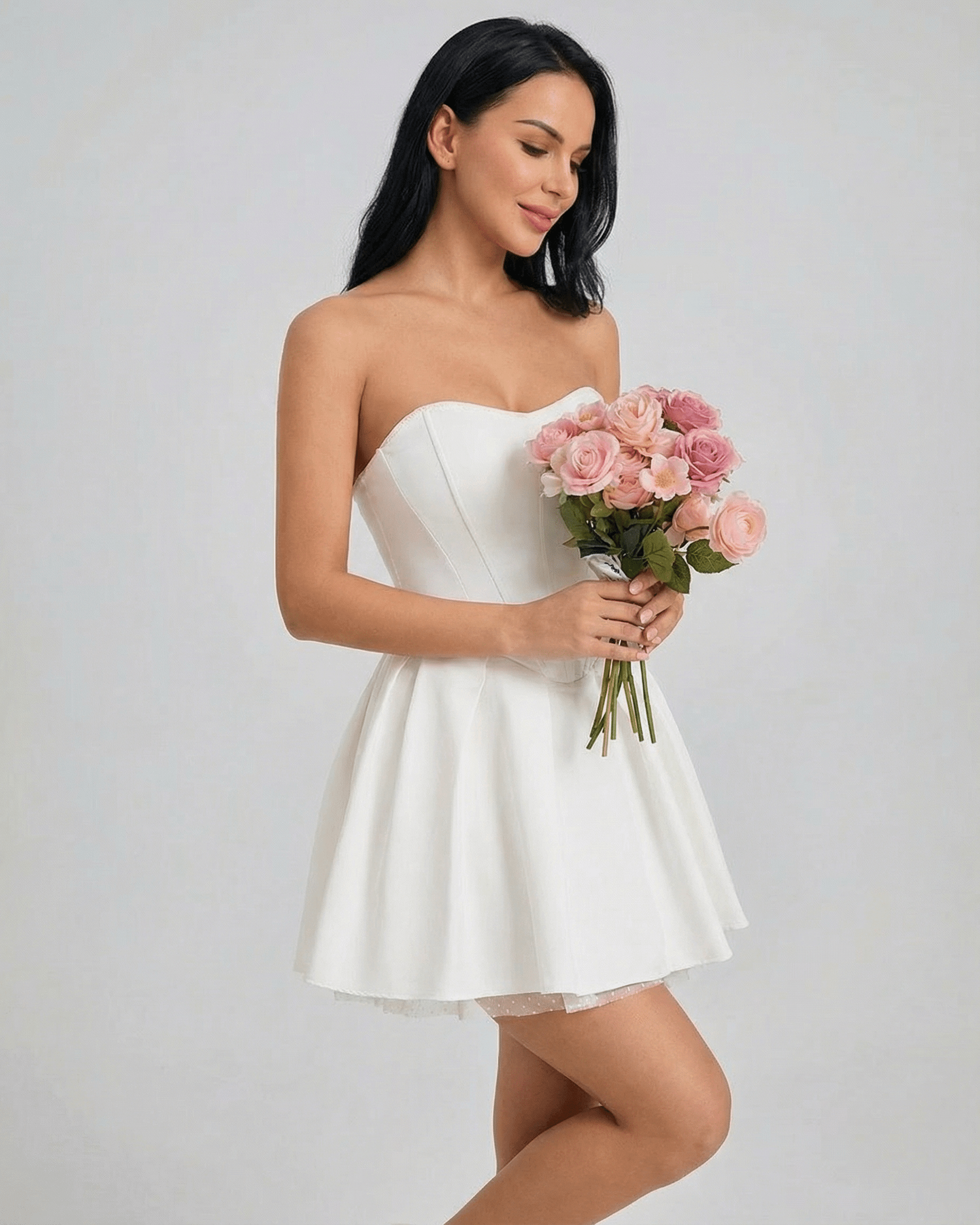 Model wearing the Celeste Mini Dress by SLIMONA, holding a bouquet of pink roses in a serene pose.