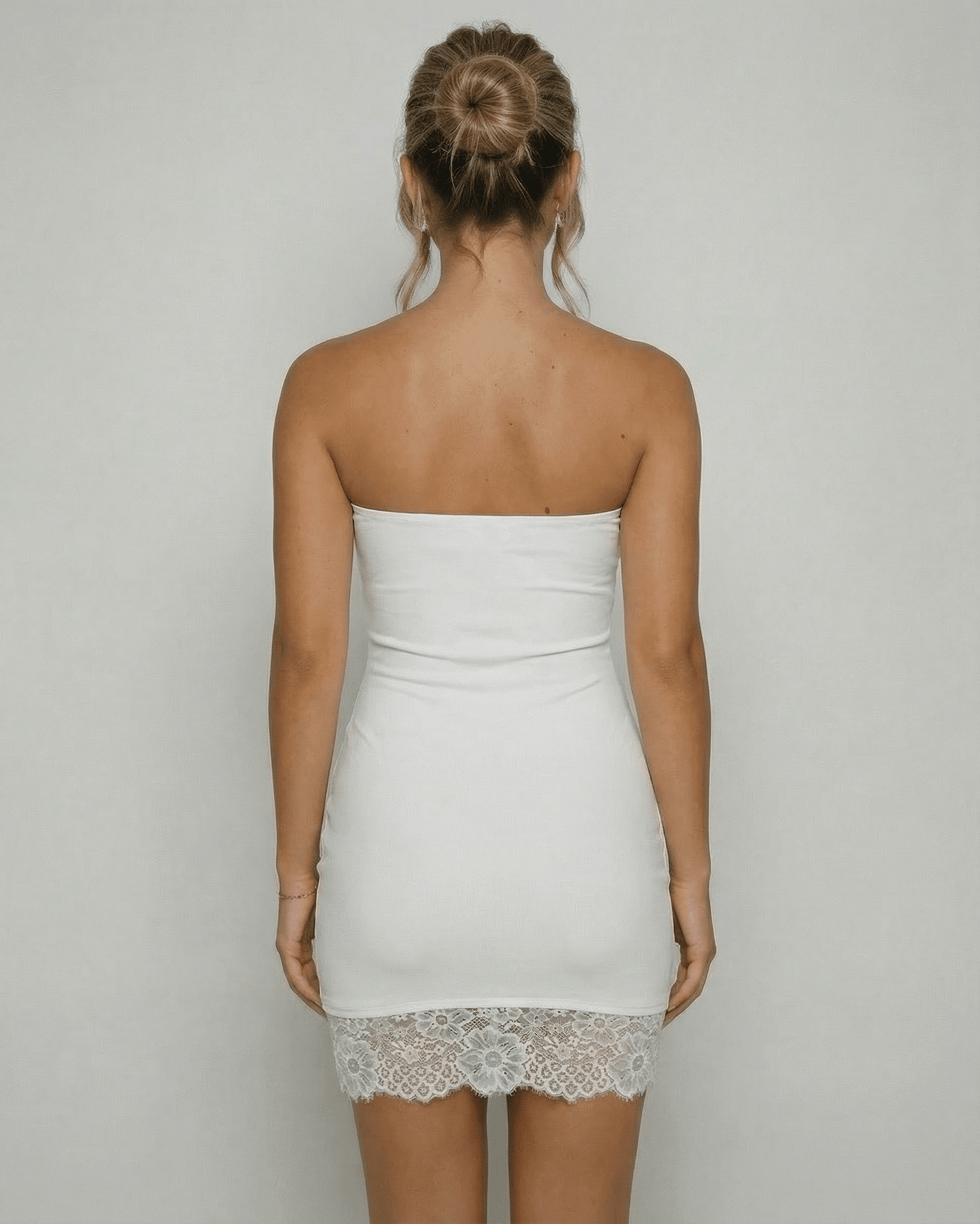 Back view of a woman wearing the Lauven Celeste Mini Dress, showcasing the strapless design and lace hem detail.