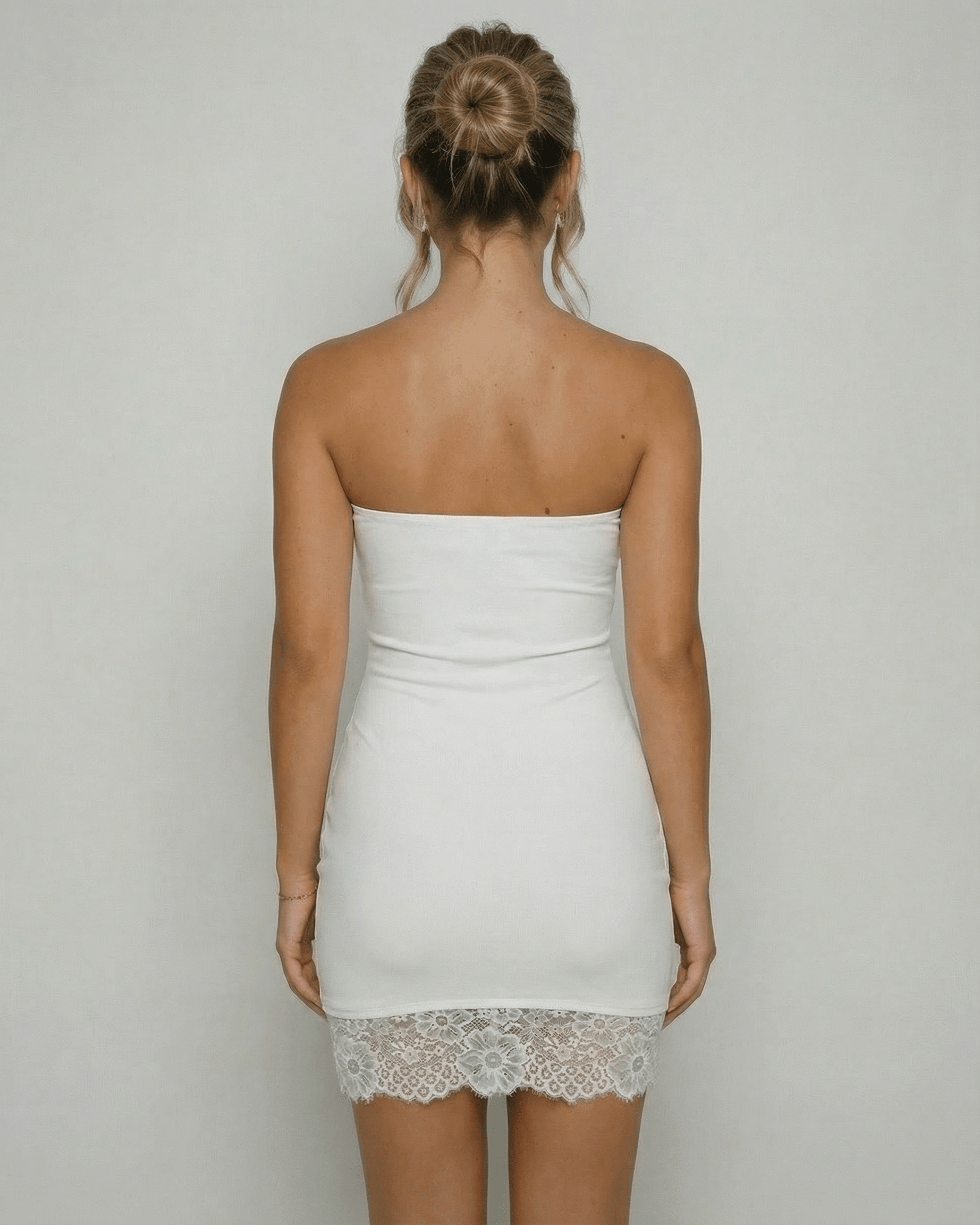 Back view of a woman wearing the Lauven Celeste Mini Dress, showcasing the strapless design and lace hem detail.