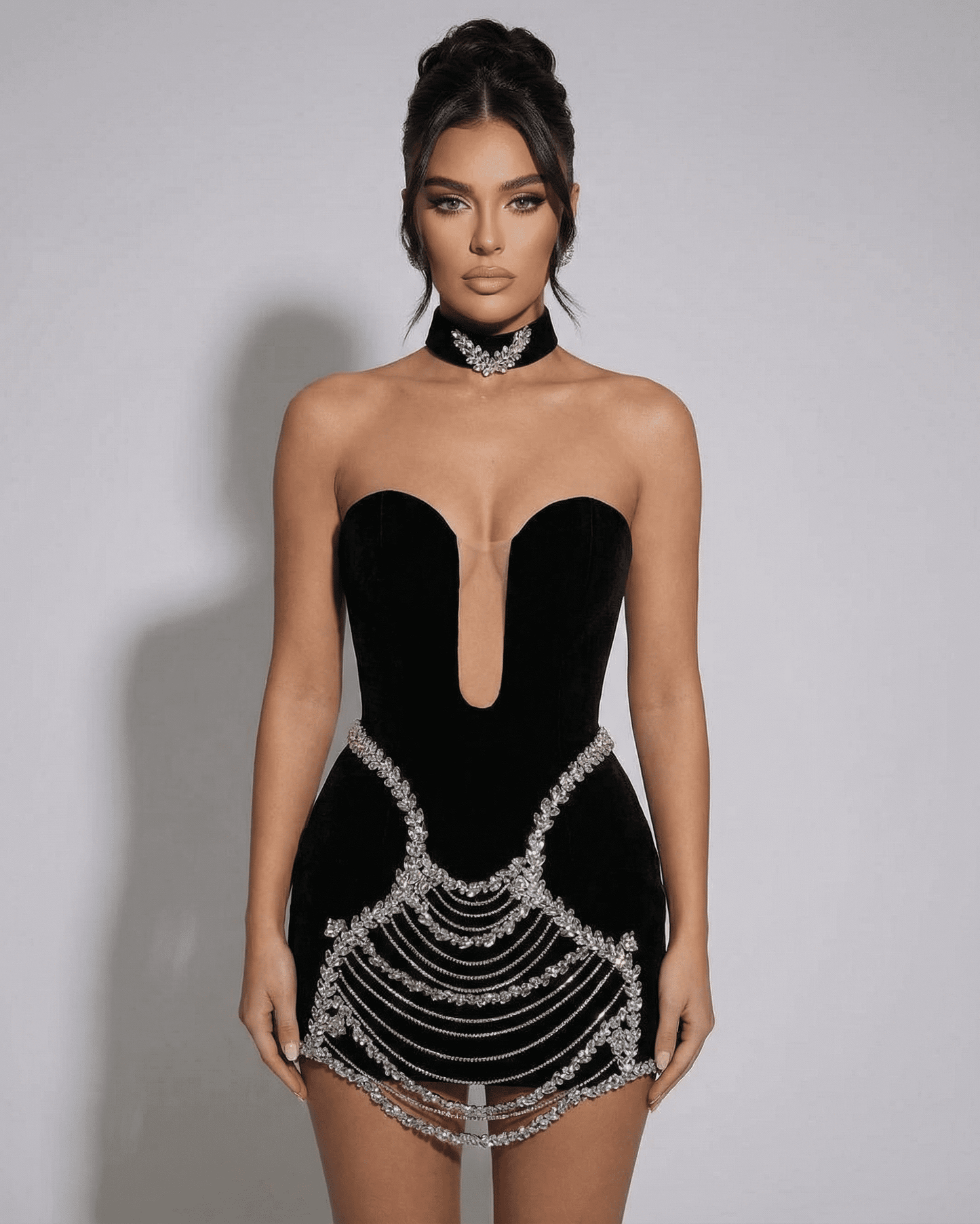 Stylish model wearing the SLIMONA Celeste Mini Dress featuring crystal rhinestone chain details and a deep V-neckline.