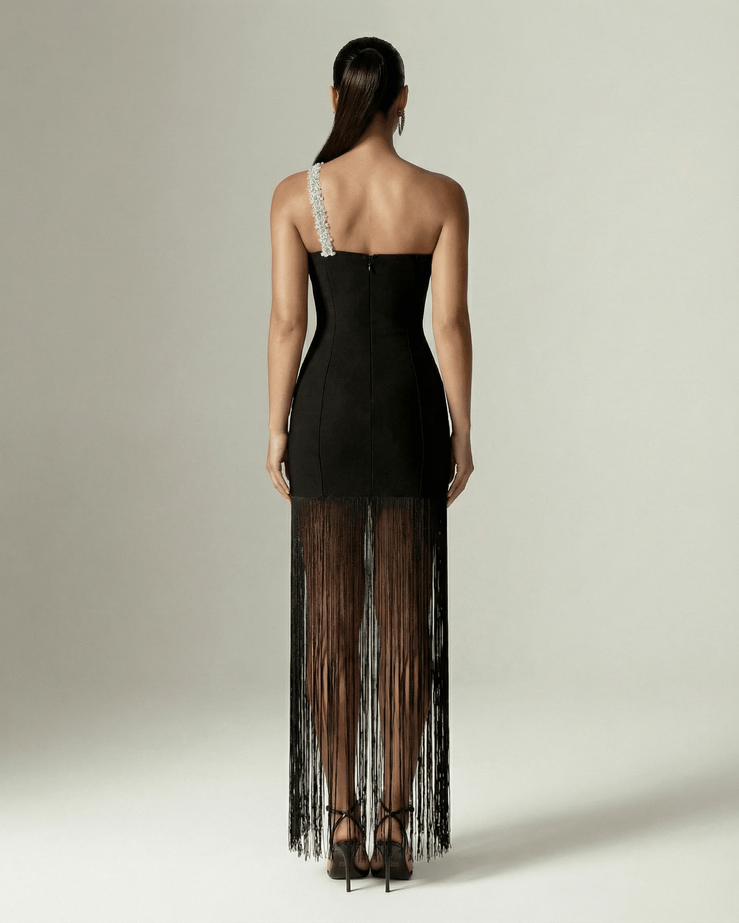 Back view of the Celestia Maxi Dress from Lauven, featuring a black one-shoulder design and elegant fringed hem.