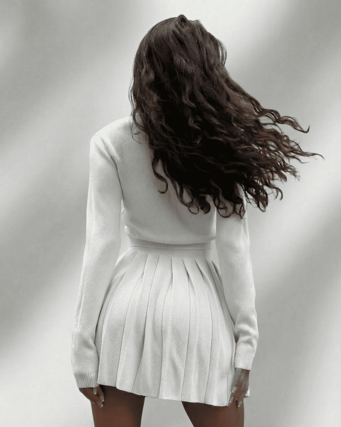 Elara Two-Piece Set by SLIMONA: Knit Cardigan & Pleated Mini Skirt, showcasing a feminine silhouette.