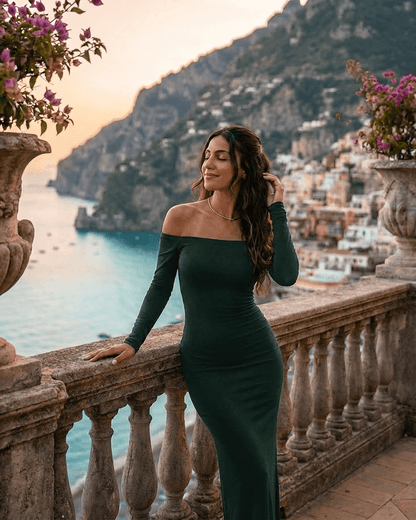 Woman in an off-shoulder Emerald Maxi Dress by SLIMONA, enjoying a sunset view by the coast.