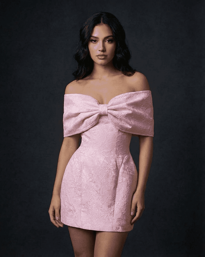 Fiora Mini Dress by SLIMONA, featuring an off-the-shoulder design with a large bowknot in soft pink.