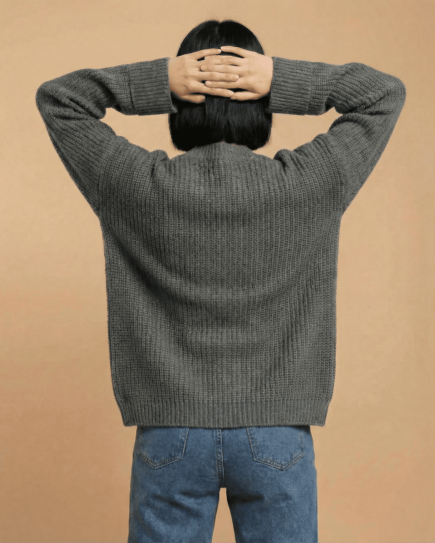 Relaxed woman wearing the Linden Cardigan from SLIMONA, showcasing the modern knit design from the back.