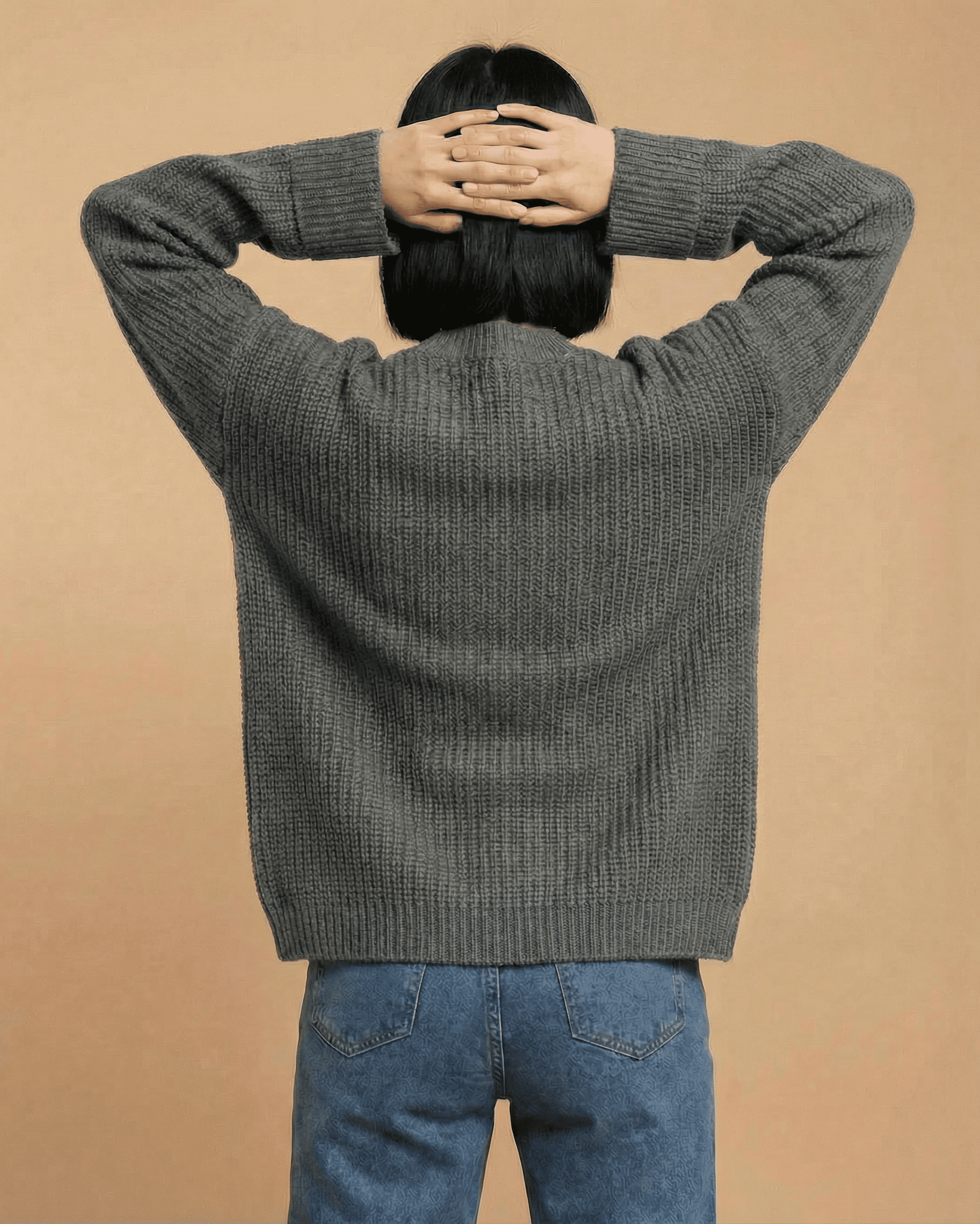 Relaxed woman wearing the Linden Cardigan from SLIMONA, showcasing the modern knit design from the back.