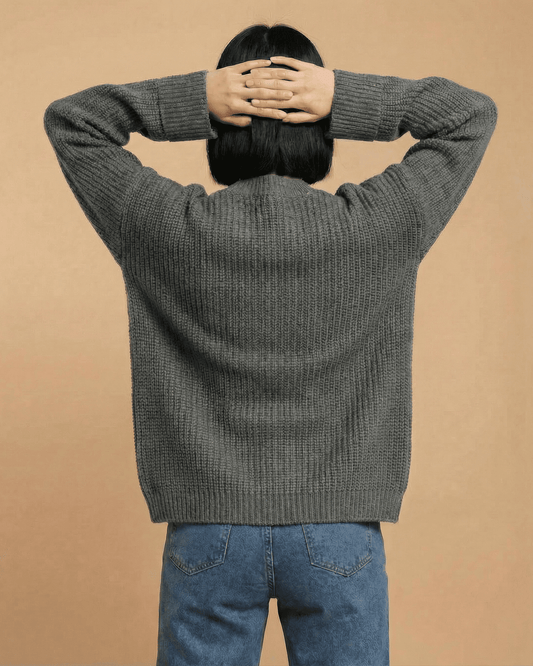 Relaxed woman wearing the Linden Cardigan from SLIMONA, showcasing the modern knit design from the back.