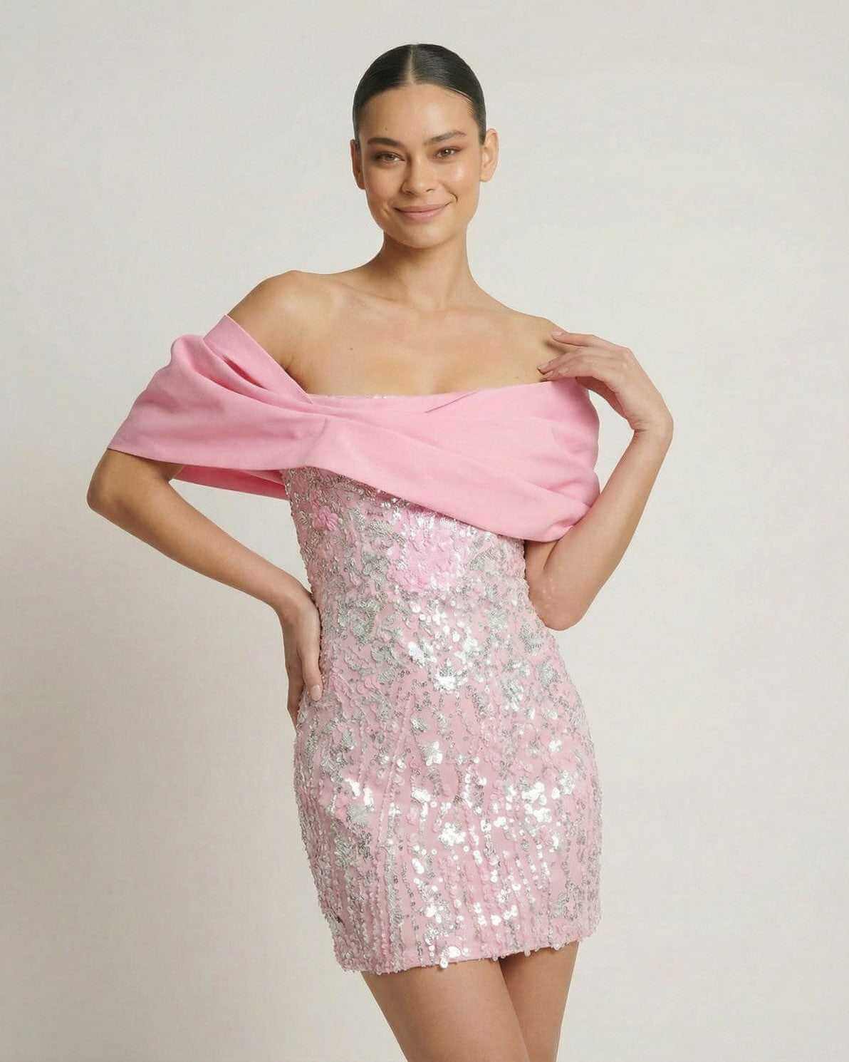 Lauven Luna Mini Dress in pink sequins with off-the-shoulder draped chest wrap, perfect for parties.