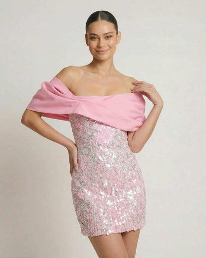 Lauven Luna Mini Dress in pink sequins with off-the-shoulder draped chest wrap, perfect for parties.