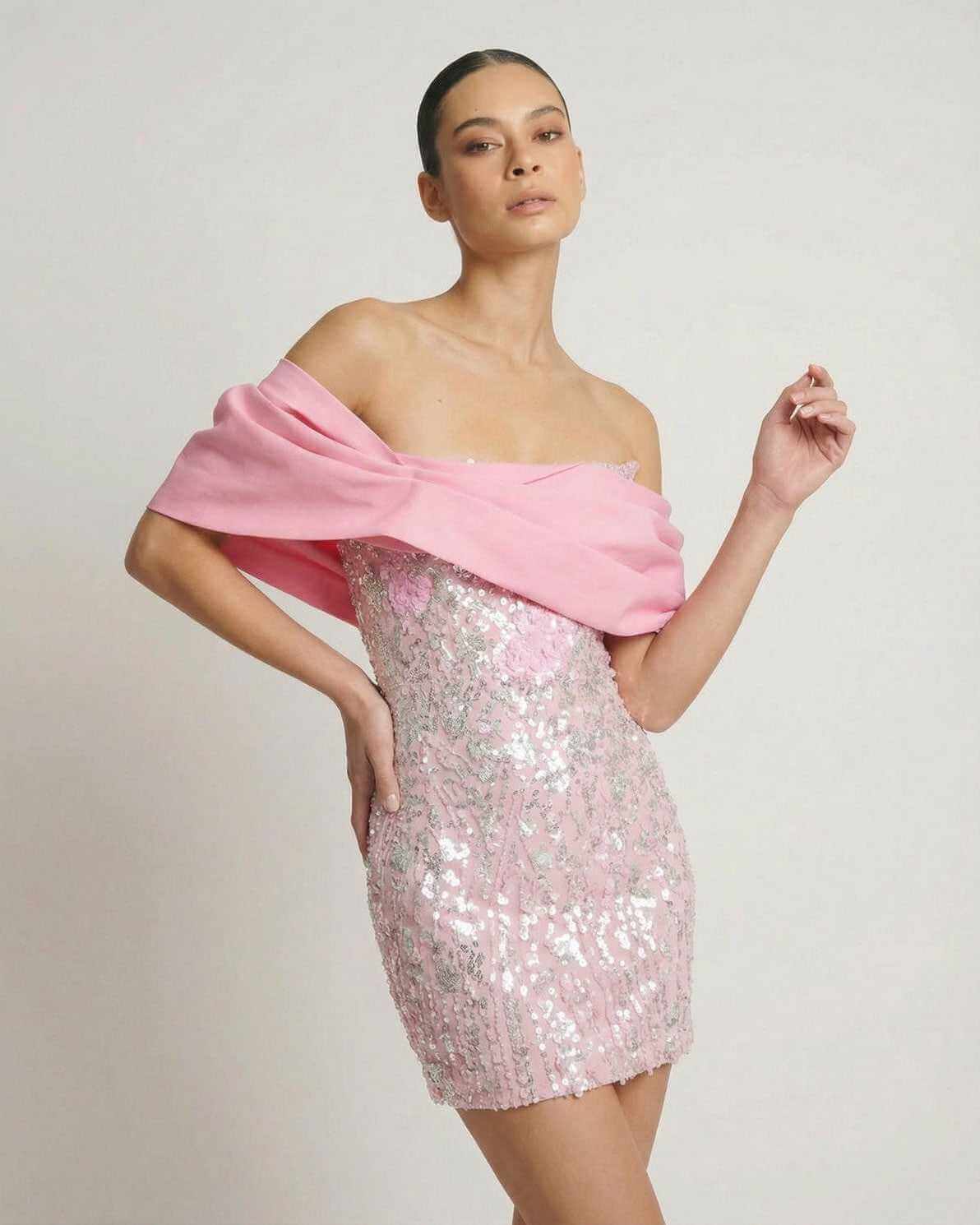 Lauven Luna Mini Dress featuring pink sequin fabric and off-the-shoulder draped detail, perfect for parties.
