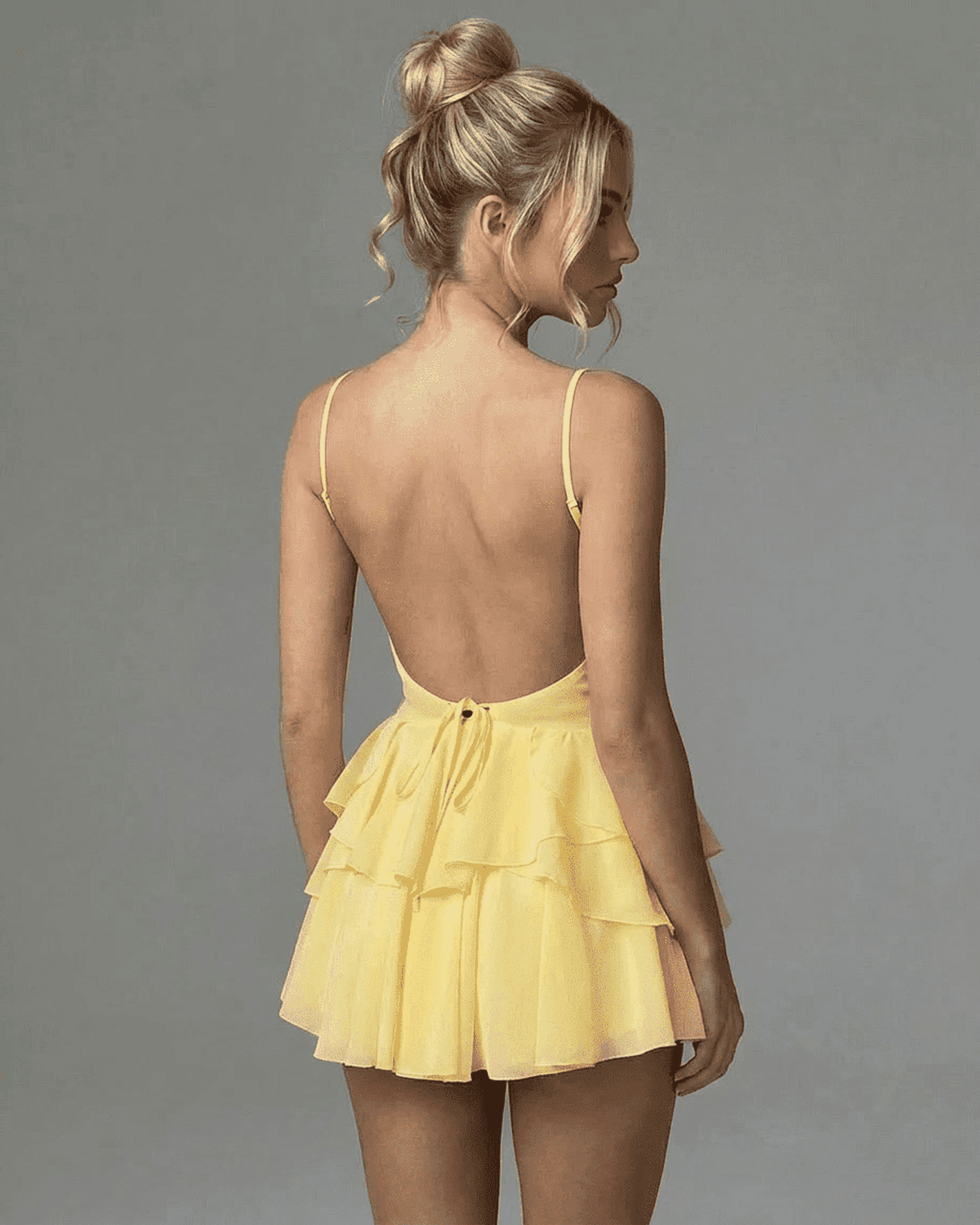 Marigold Mini Dress by SLIMONA - Back view of a ruffled yellow mini dress showcasing elegant spaghetti straps.