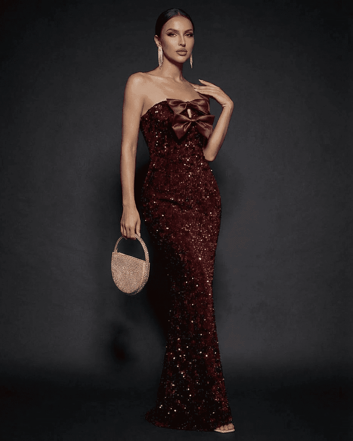 Model wearing SLIMONA Marquise Maxi Dress with strapless design, satin bow, and sparkling sequins for elegant evening occasion.