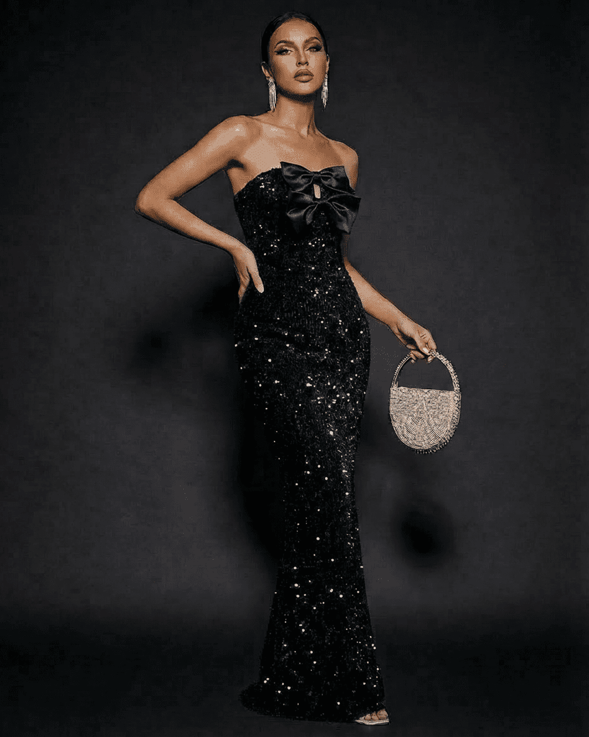 Elegant model wearing Noir Maxi Dress by SLIMONA, a strapless sequin evening gown with satin bows.