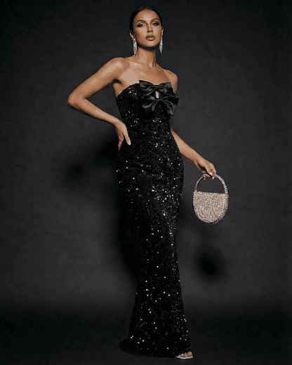 Elegant model wearing Noir Maxi Dress by SLIMONA, a strapless sequin evening gown with satin bows.