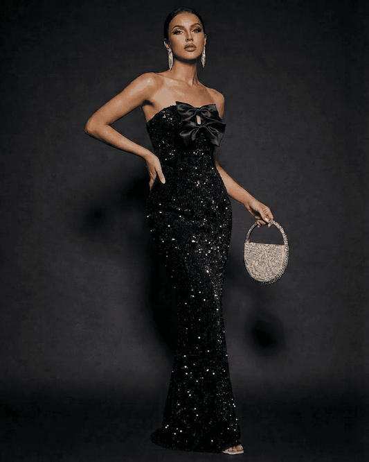 Elegant model wearing Noir Maxi Dress by SLIMONA, a strapless sequin evening gown with satin bows.