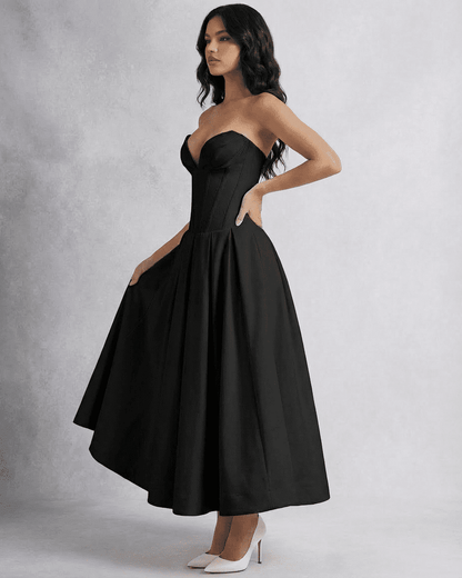 Model wearing the Nova Midi Dress by SLIMONA, a sleek strapless corset A-line dress in black.