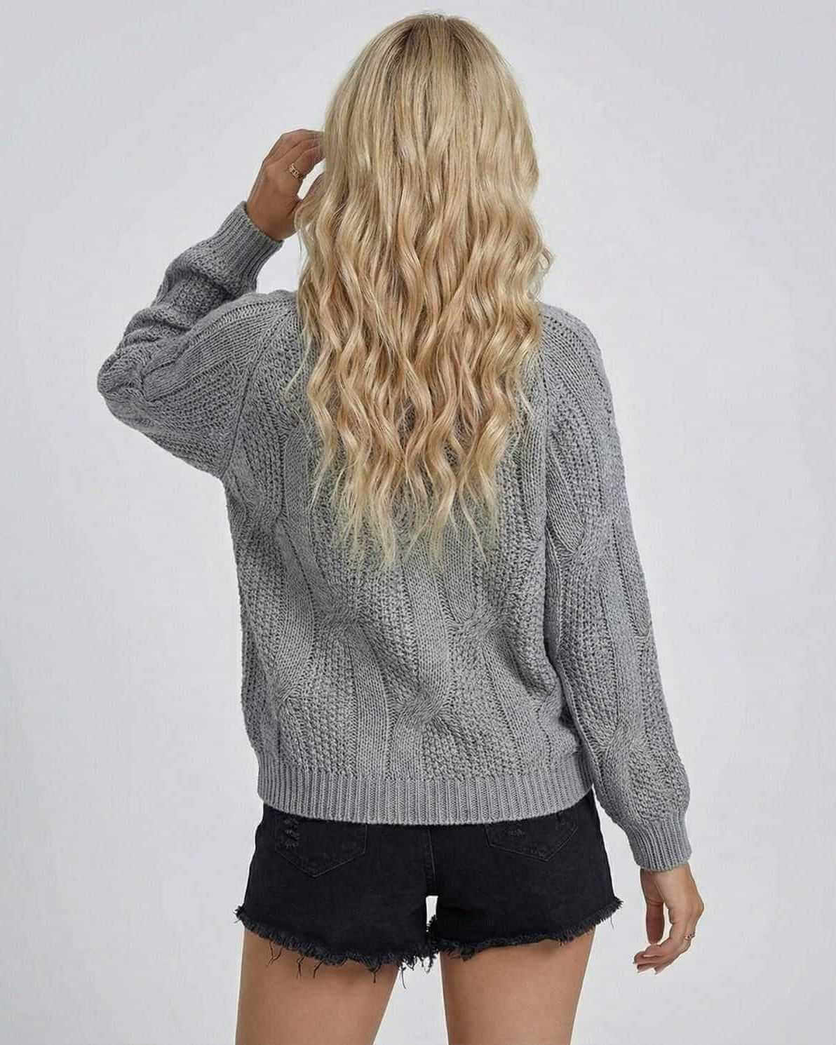 Back view of a woman wearing the grey Orion Sweater by Lauven, showcasing its cable-knit texture and long sleeves.